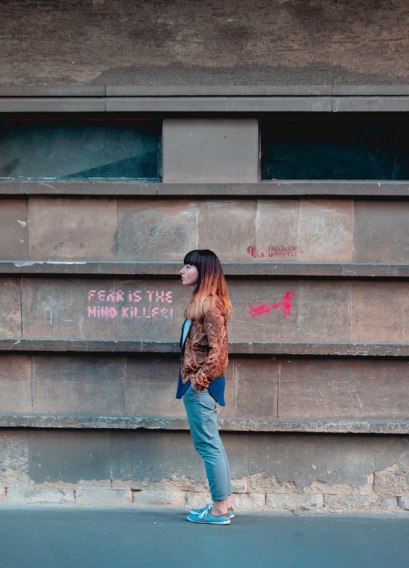 girl standing by graffiti that says "fear is the mind killer"