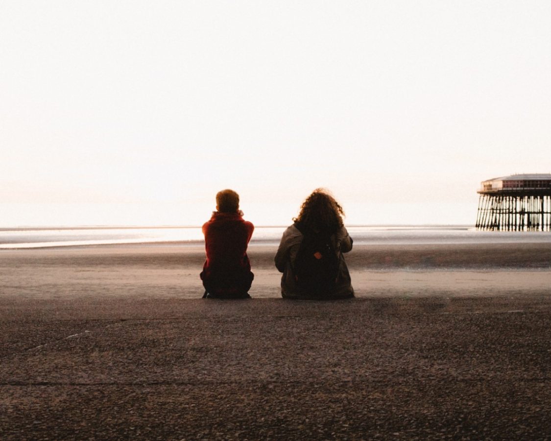 a girl and a guy staring out on a beach
