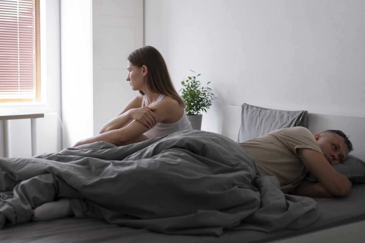 Disappointed couple in bed with plant in background